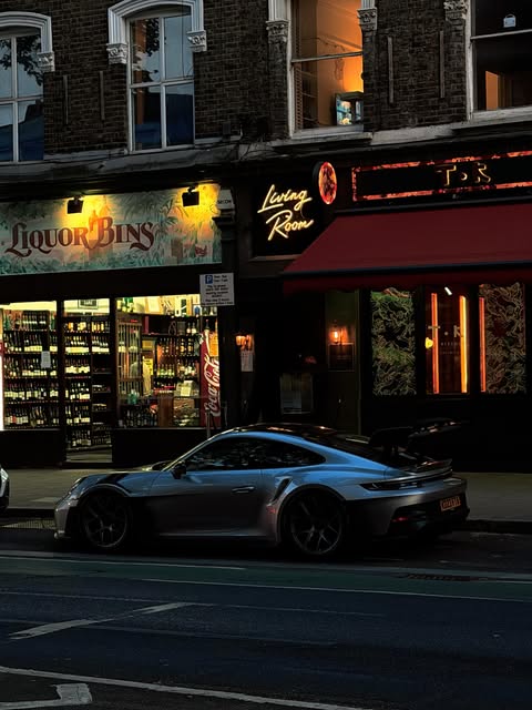 Sports car parked outside illuminated late-night shopfronts