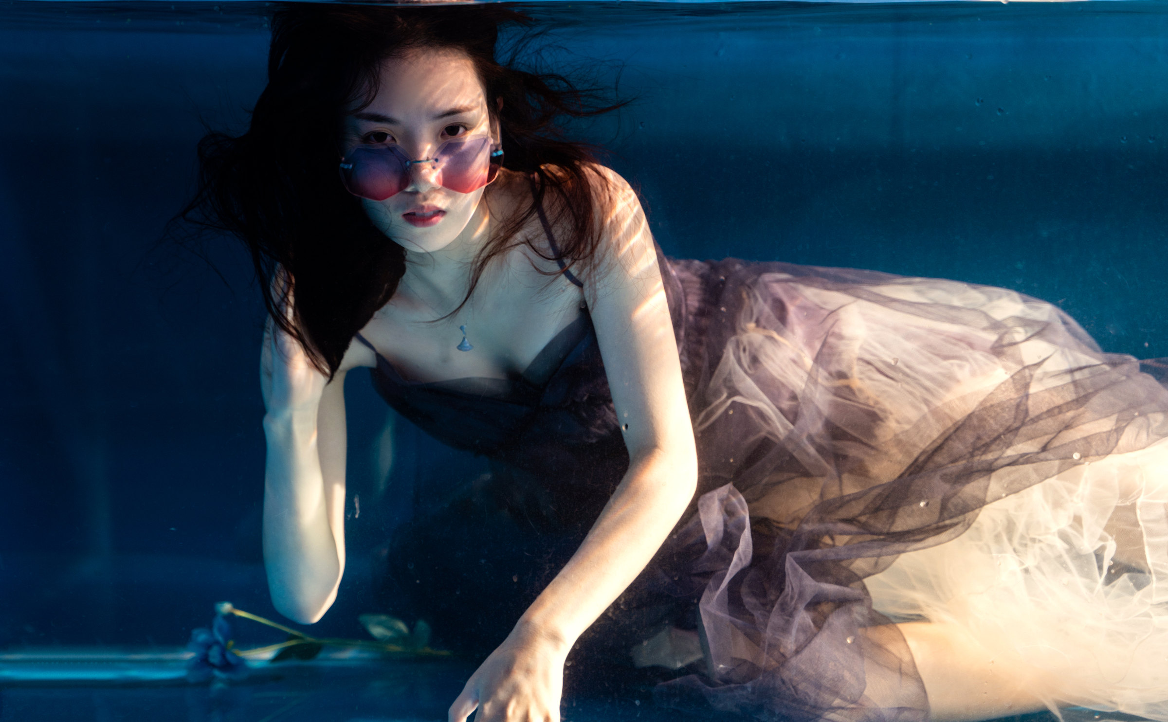 A woman approaches the glass while submerged