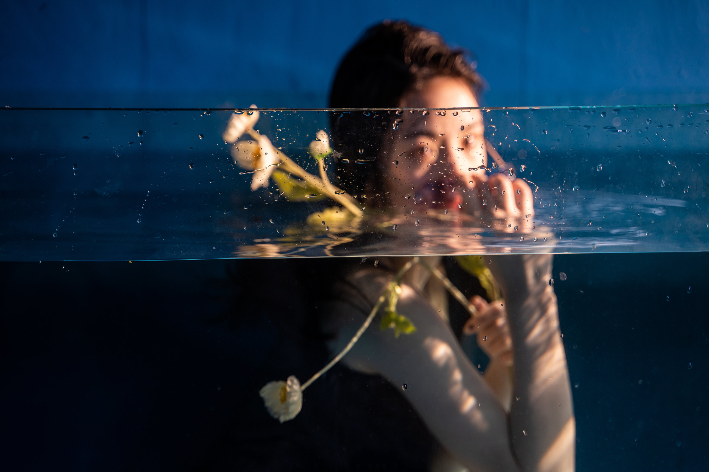 A woman and white flowers divided by a waterline