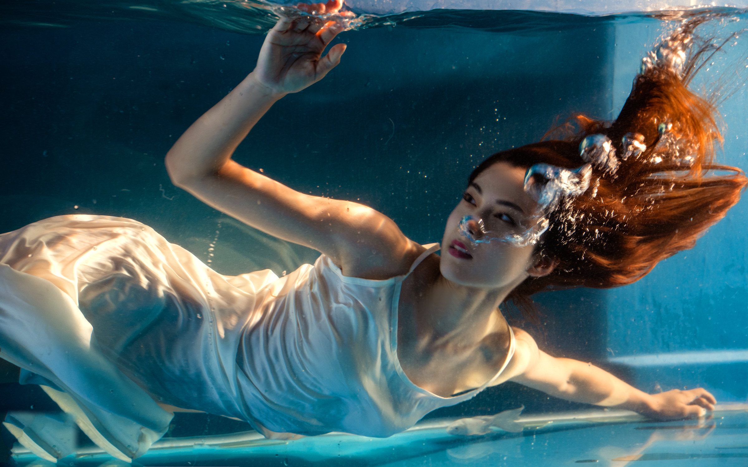 A woman in white moves underwater