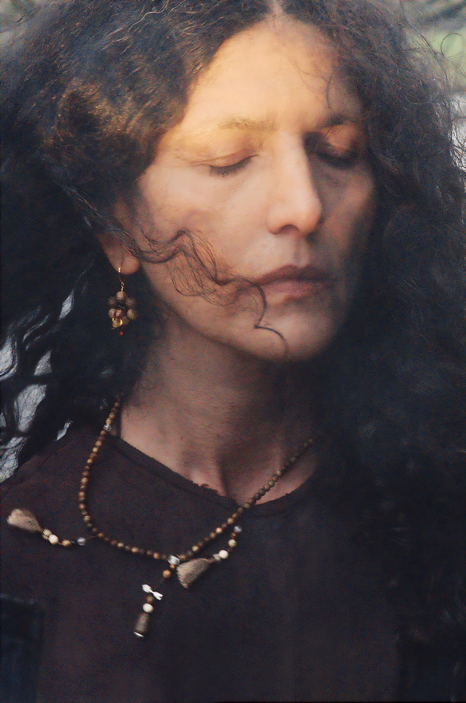 Close colour portrait with eyes closed and hair moving across the face