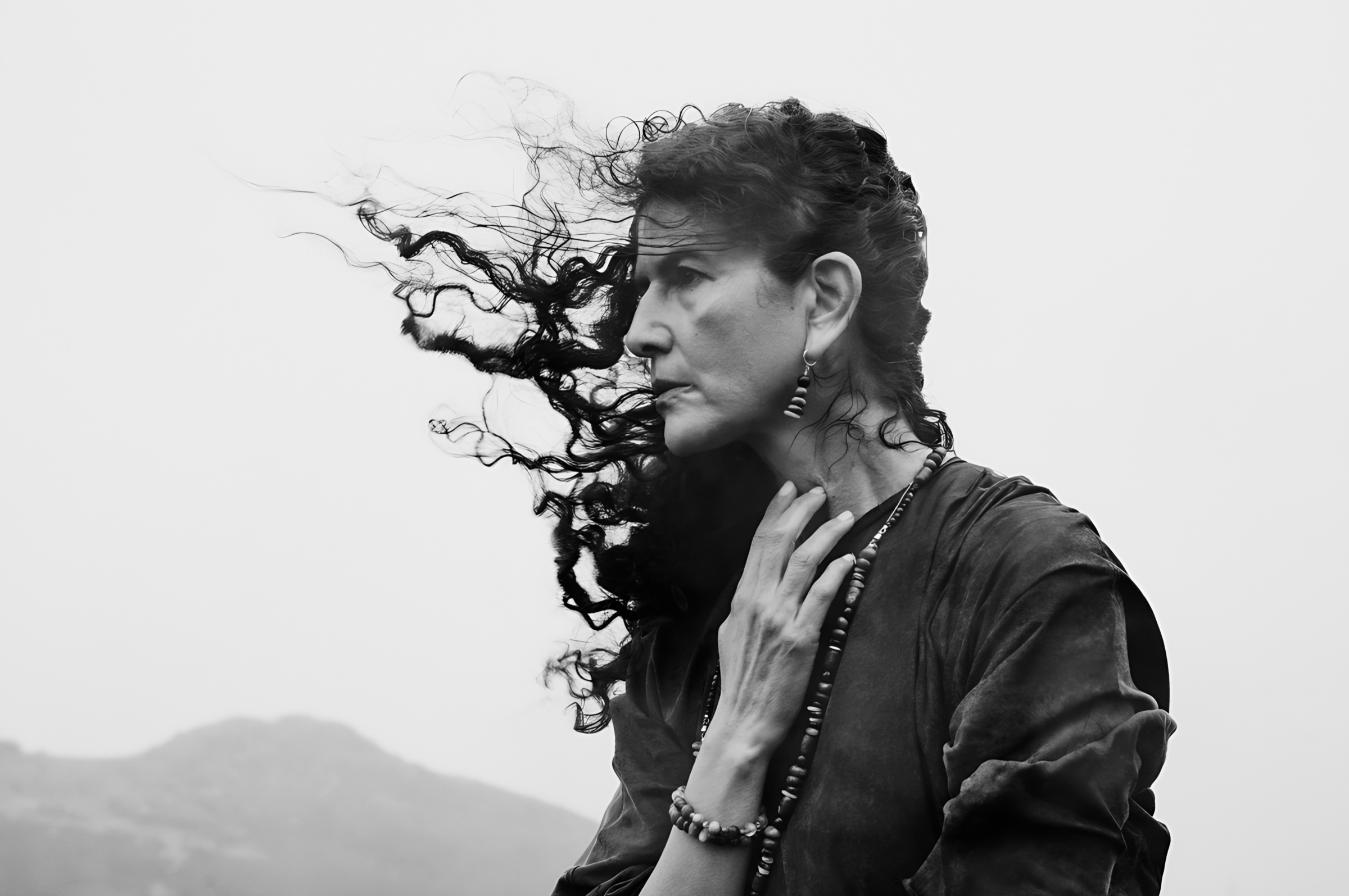 Black-and-white portrait of a figure whose hair is carried by the wind